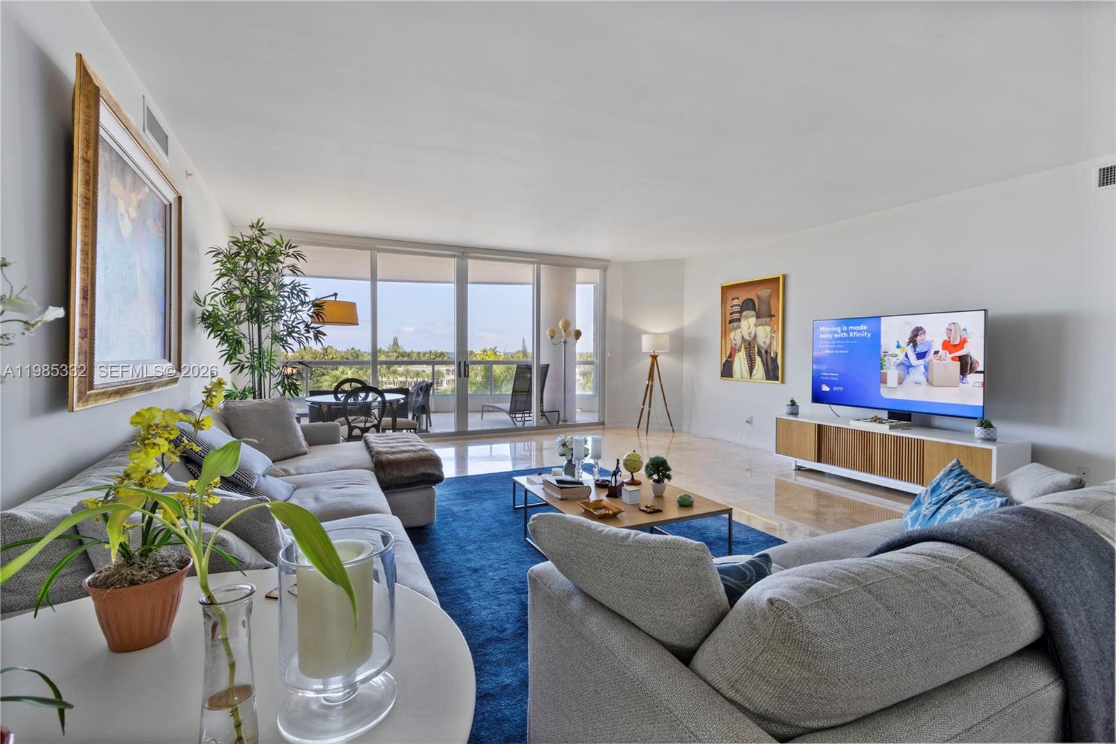 A bright living room features a blue area rug, gray sofas, and a balcony view — 21050 Point Pl # 604, Aventura FL 33180, AVENTURA, FL