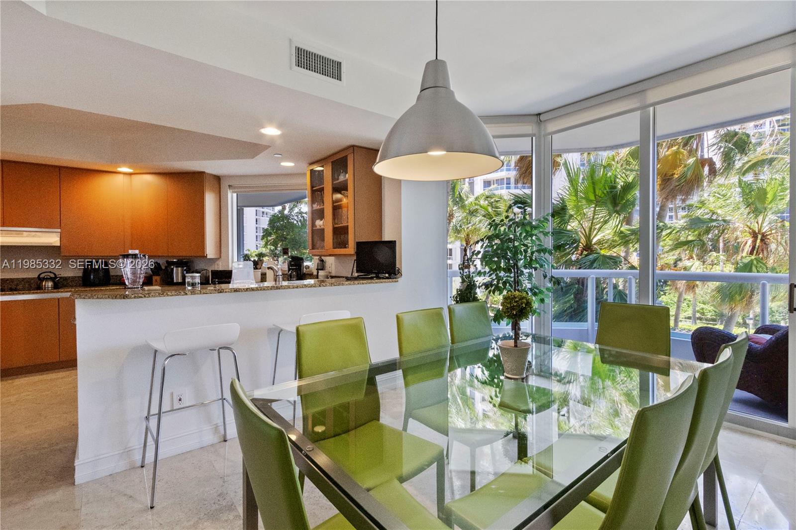 A dining area with a glass table and green chairs sits beside a kitchen — 21050 Point Pl # 604, Aventura FL 33180, AVENTURA, FL