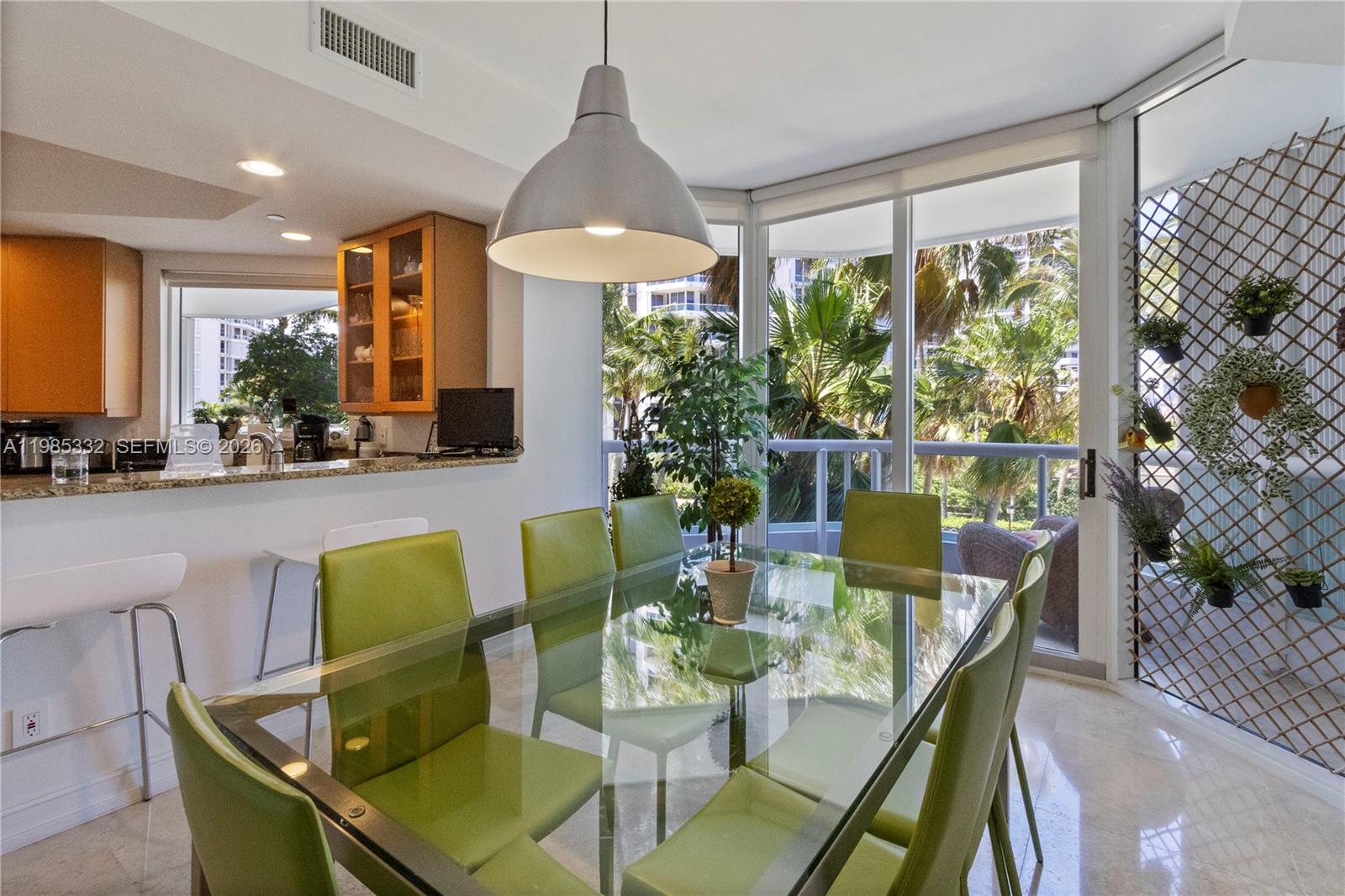 A dining area with a glass table, lime green chairs, and a view of palm trees — 21050 Point Pl # 604, Aventura FL 33180, AVENTURA, FL