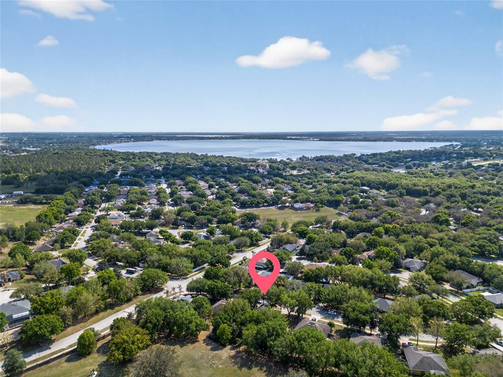 An aerial view shows a residential neighborhood with a pink location pin over a house — 1305 WINDY BLUFF DRIVE, MINNEOLA, FL