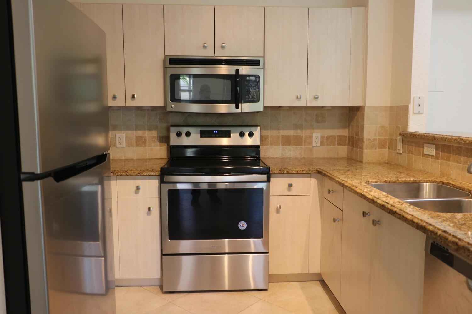 A kitchen features light wood cabinets, stainless steel appliances, and tan granite countertops — 1803 N Flagler Drive # 212, West Palm Beach FL 33407, WEST PALM BEACH, FL