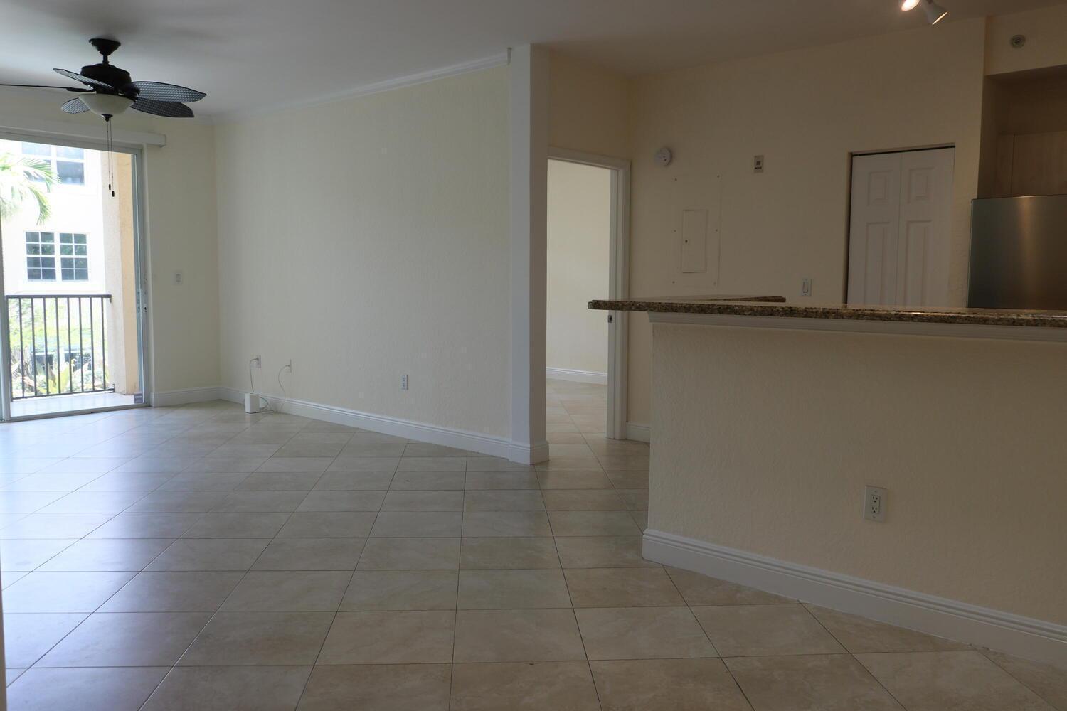 An open-concept living area with tile floors, a ceiling fan, and a kitchen breakfast bar — 1803 N Flagler Drive # 212, West Palm Beach FL 33407, WEST PALM BEACH, FL