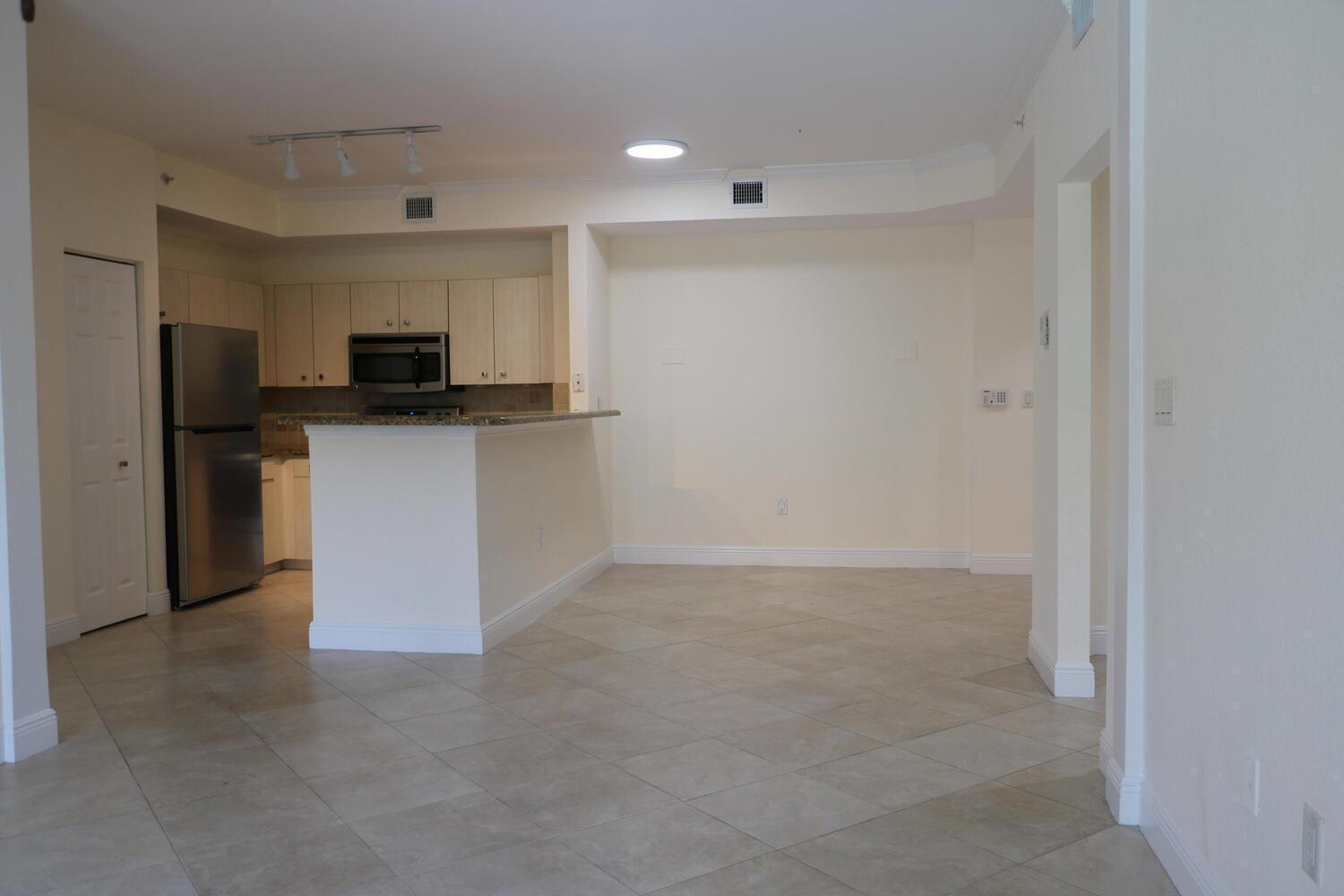 An open-concept kitchen with light wood cabinets, stainless steel appliances, and tile flooring — 1803 N Flagler Drive # 212, West Palm Beach FL 33407, WEST PALM BEACH, FL