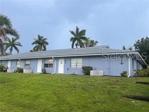 A single-story light blue residential building with a gray shingled roof and palm trees — 810 KINGS COURT UNIT F, PUNTA GORDA, FL
