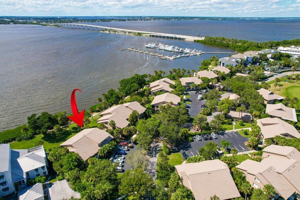 An aerial view shows a waterfront condominium complex with a red arrow pointing toward trees — 218 NE Edgewater Drive # 218, Hutchinson Island FL 34996, HUTCHINSON ISLAND, FL