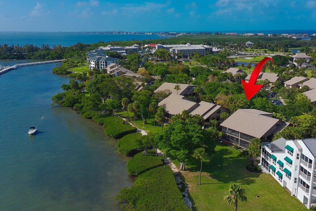 An aerial view shows waterfront condominiums surrounded by lush trees and a grassy lawn — 218 NE Edgewater Drive # 218, Hutchinson Island FL 34996, HUTCHINSON ISLAND, FL
