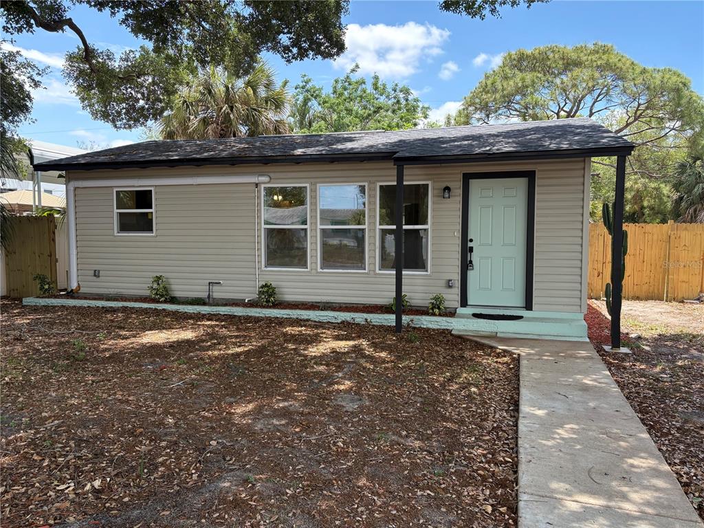 A single-story house with light tan siding, a mint green door, and a concrete walkway — 6948 DARTMOUTH AVENUE N, ST PETERSBURG, FL