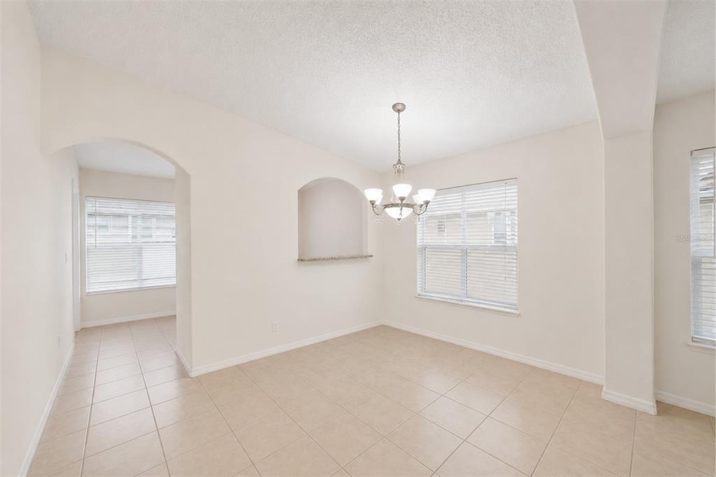 A dining room with tile flooring, a chandelier, and an arched wall niche — 2848 OSPREY COVE PLACE UNIT 204, KISSIMMEE, FL