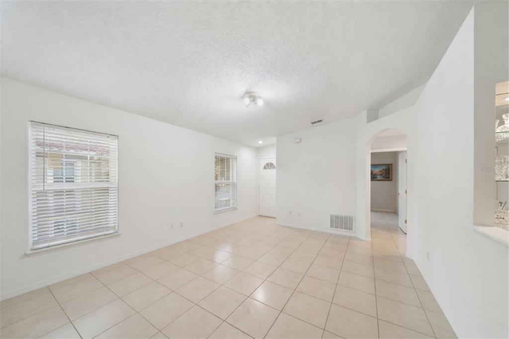 An empty room with white walls, tile flooring, two windows, and an arched doorway — 2848 OSPREY COVE PLACE UNIT 204, KISSIMMEE, FL