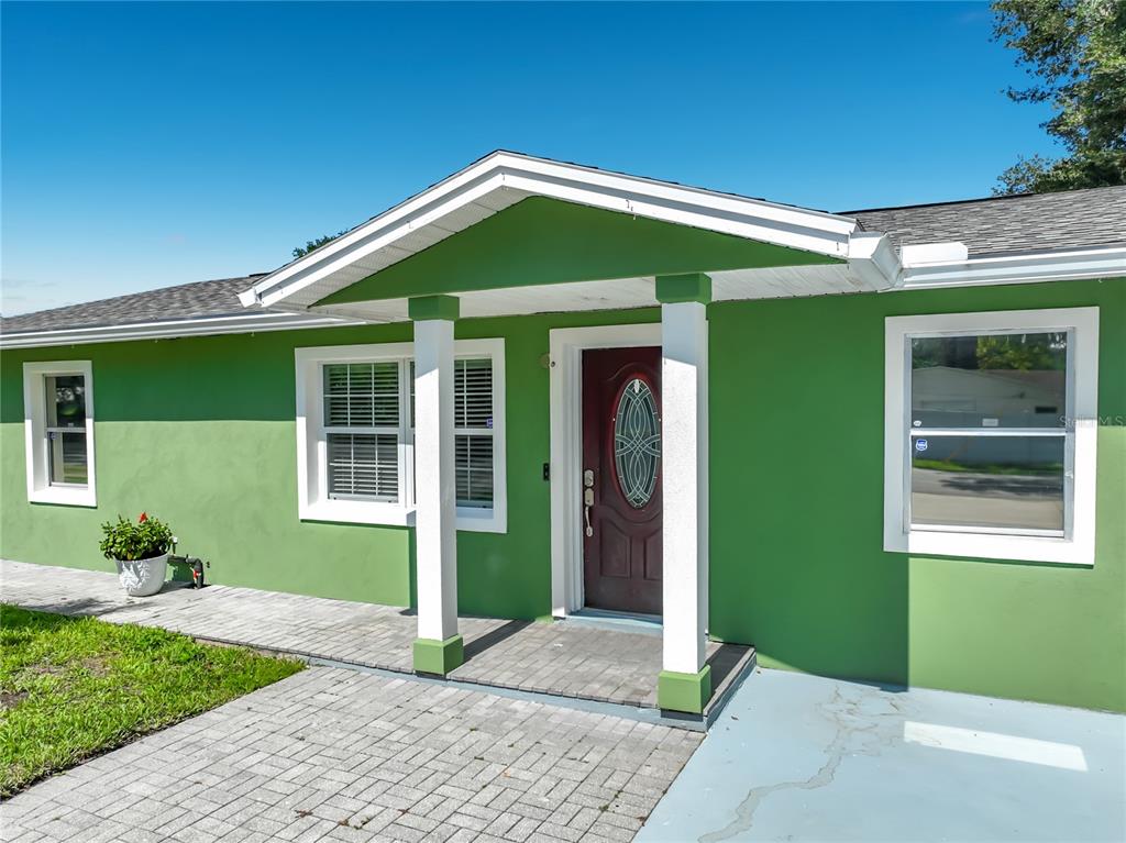 A bright green house exterior features a covered entryway with white columns and a door — 3312 S FOREST STREET, ORLANDO, FL