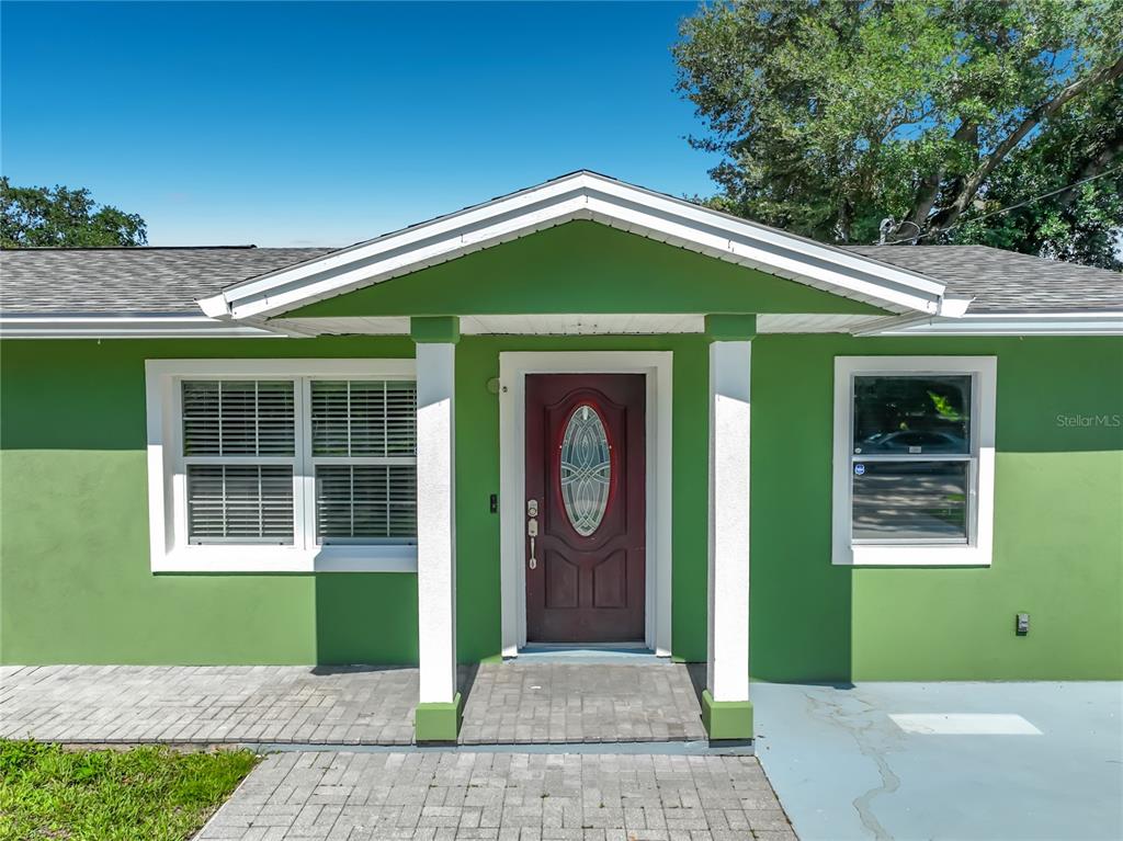 A green house exterior features a front door with an oval glass insert and columns — 3312 S FOREST STREET, ORLANDO, FL