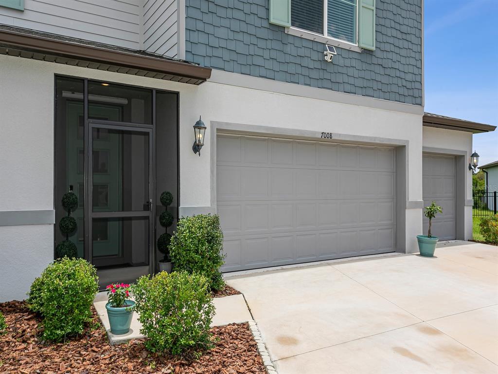 A bright entryway features a wooden console table, a large mirror, and a modern light fixture — 7008 NORRIS LANDING PLACE, PARRISH, FL