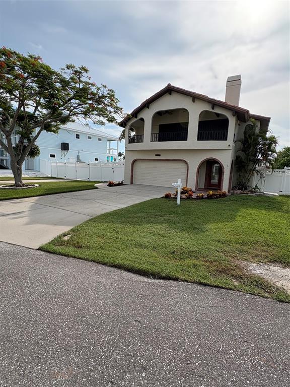 A two-story house with a beige stucco exterior, arched balconies, and a concrete driveway — 15810 REDINGTON DRIVE, REDINGTON BEACH, FL