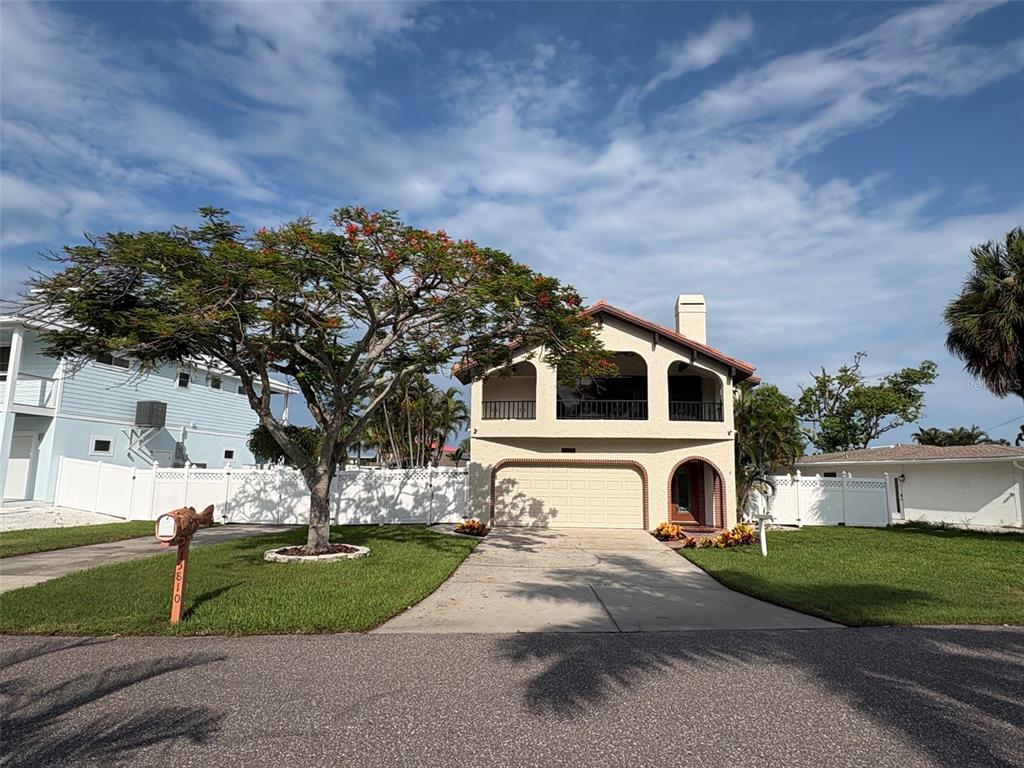 A two-story house with a garage, a large tree, and a white fence in front — 15810 REDINGTON DRIVE, REDINGTON BEACH, FL