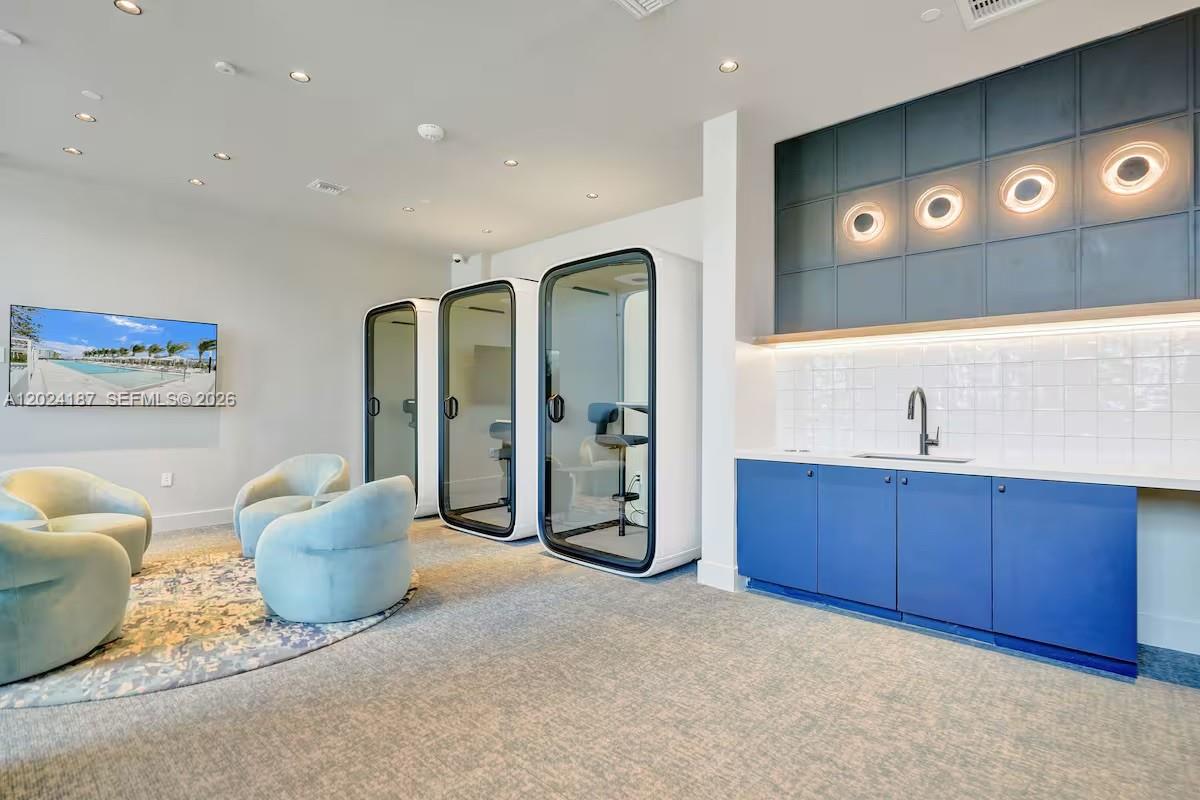 A modern lounge area features two private work pods, blue cabinetry, and a wall-mounted television — 580 72 ST # 1804, Miami Beach 34553, MIAMI BEACH, FL