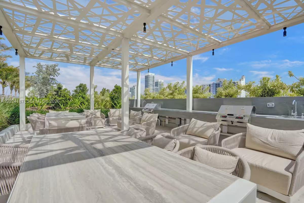 An outdoor patio features a white pergola, dining table, lounge seating, and a built-in grill — 580 72 ST # 1804, Miami Beach 34553, MIAMI BEACH, FL