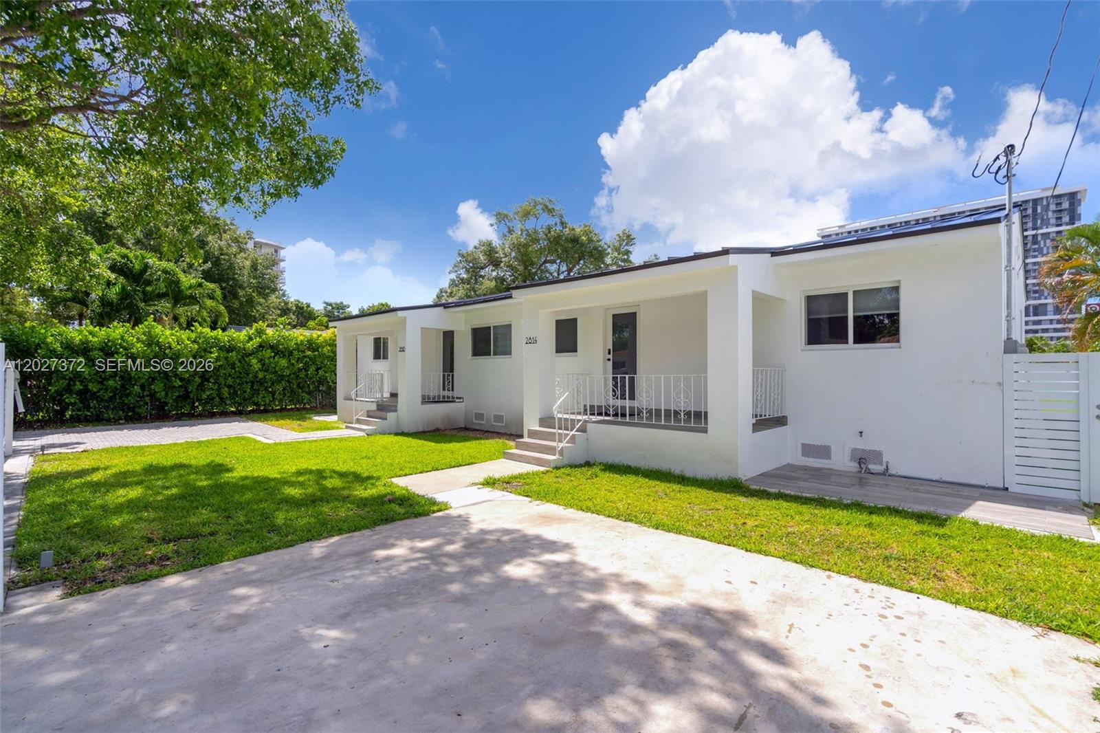 A white, single-story duplex building features covered porches, concrete walkways, and a grassy front yard — 2814 SW 26th St # 2814, Miami FL 33133, MIAMI, FL