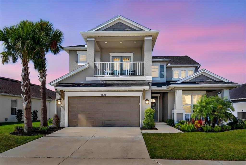 A two-story suburban house features a front-facing garage, a second-story balcony, and palm trees — 5825 FIELDMOOR COURT, PALMETTO, FL