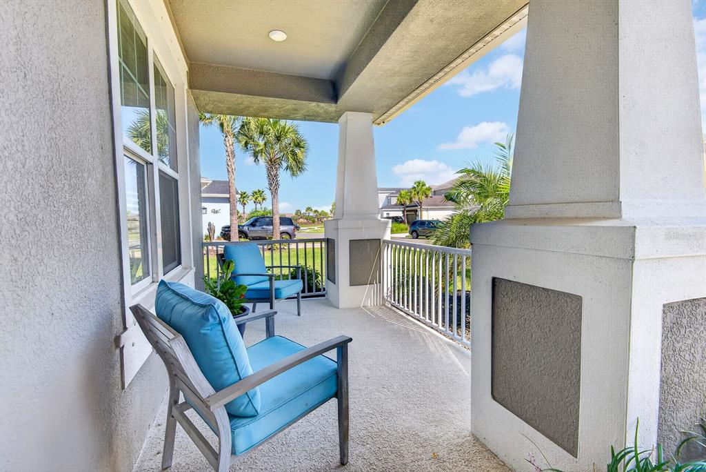 A covered front porch features two blue chairs and white columns overlooking a residential street — 5825 FIELDMOOR COURT, PALMETTO, FL
