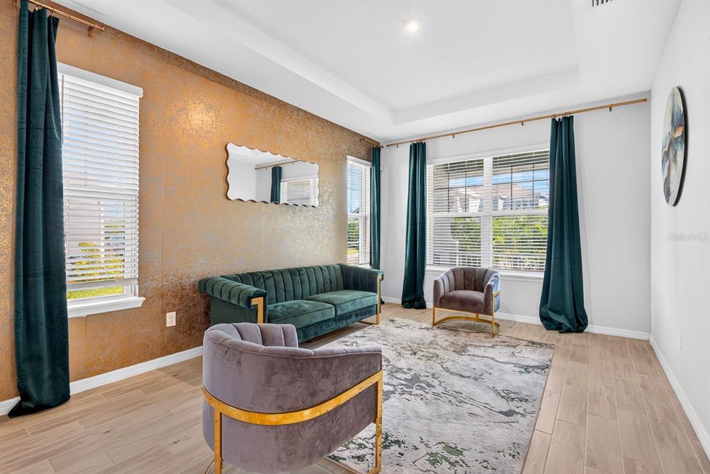 A living room features a metallic gold accent wall, green velvet sofa, and two armchairs — 5825 FIELDMOOR COURT, PALMETTO, FL