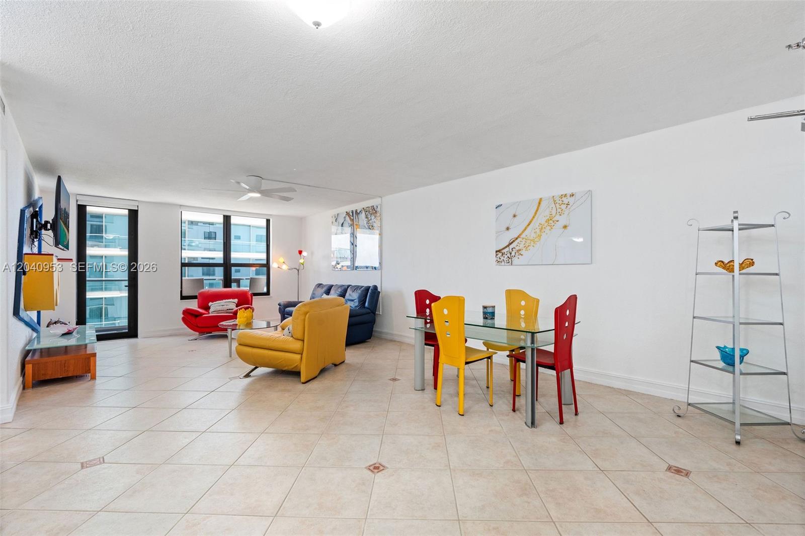 A living and dining area features tile flooring, colorful furniture, and a glass dining table — 10185 Collins Ave # 521, Bal Harbour FL 33154, BAL HARBOUR, FL