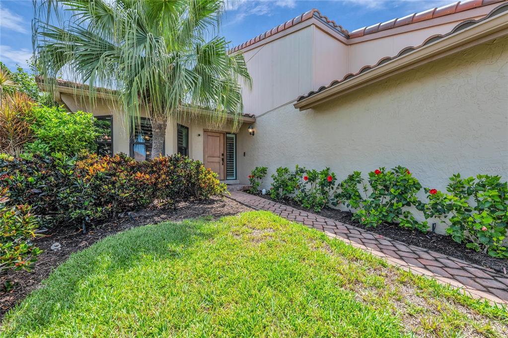A brick walkway leads to the wooden front door of a house with stucco walls — 2350 HARBOUR OAKS DRIVE, LONGBOAT KEY, FL