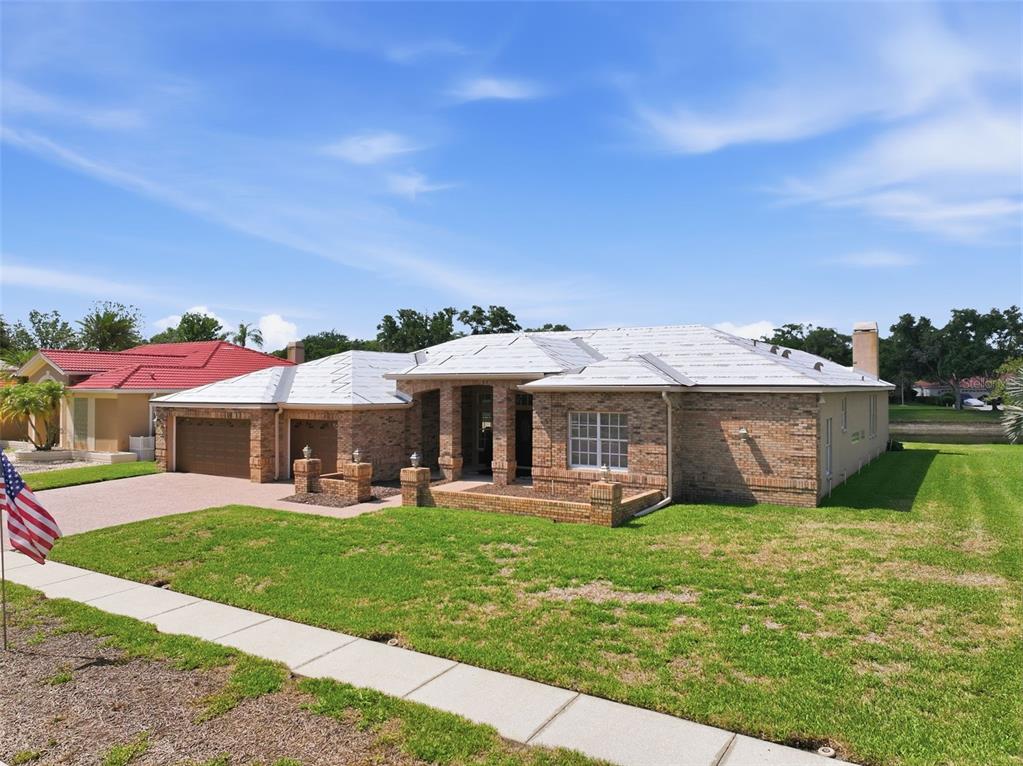 A single-story brick house with a white underlayment roof and a two-car garage — 3166 STERLING STREET, TARPON SPRINGS, FL