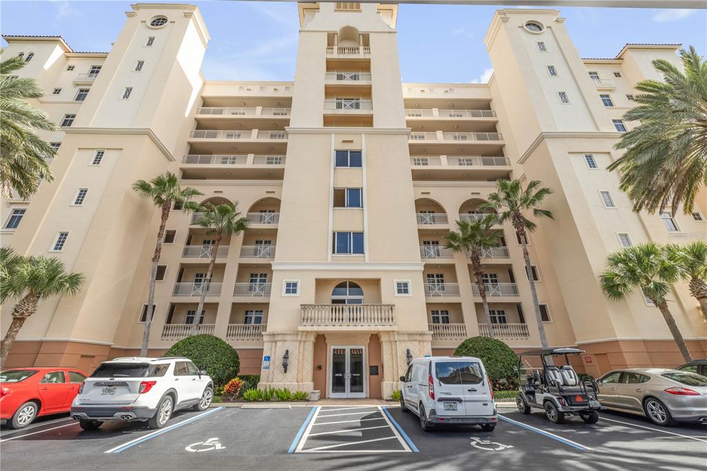 A multi-story beige apartment building features balconies, a central entrance, and a parking lot — 261 MINORCA BEACH WAY UNIT 406, NEW SMYRNA BEACH, FL