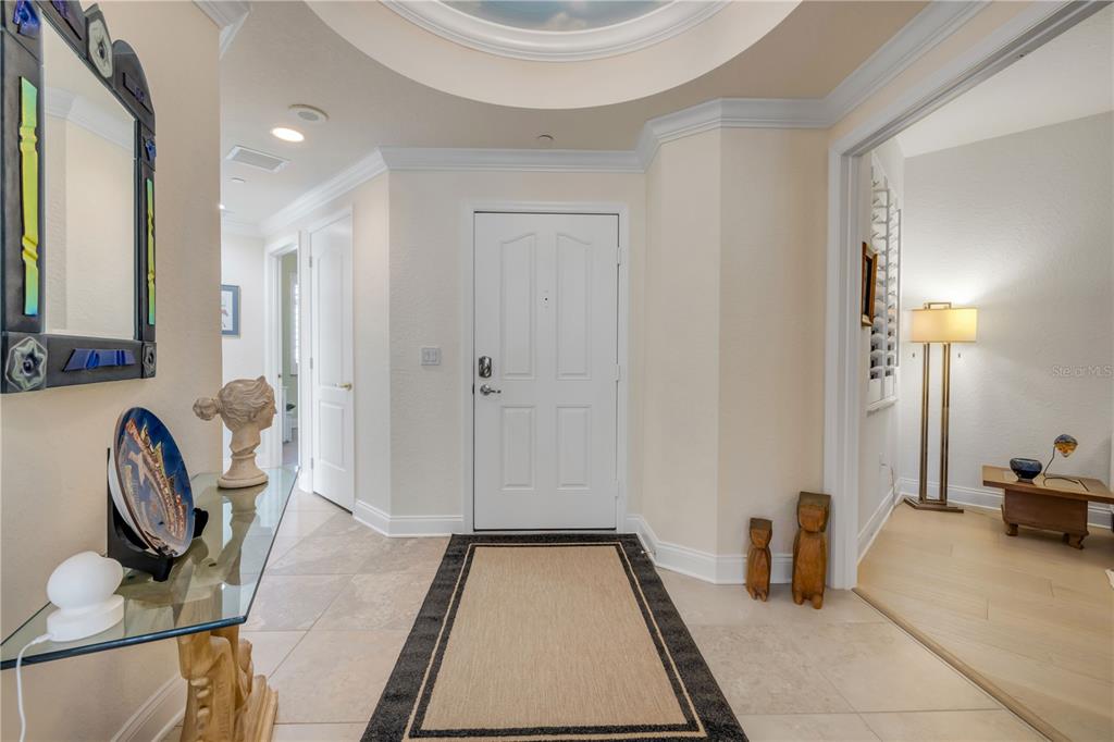 An entryway with a white door, tile flooring, a rug, and a glass console table — 261 MINORCA BEACH WAY UNIT 406, NEW SMYRNA BEACH, FL