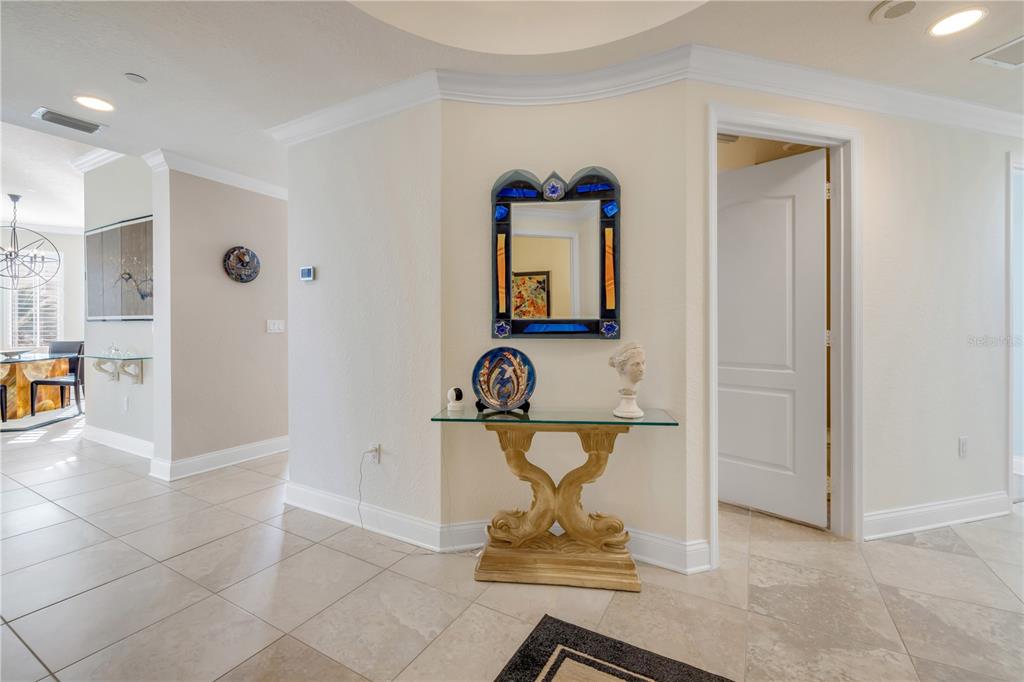 A glass-topped console table with a decorative mirror sits in a tiled entryway hallway — 261 MINORCA BEACH WAY UNIT 406, NEW SMYRNA BEACH, FL