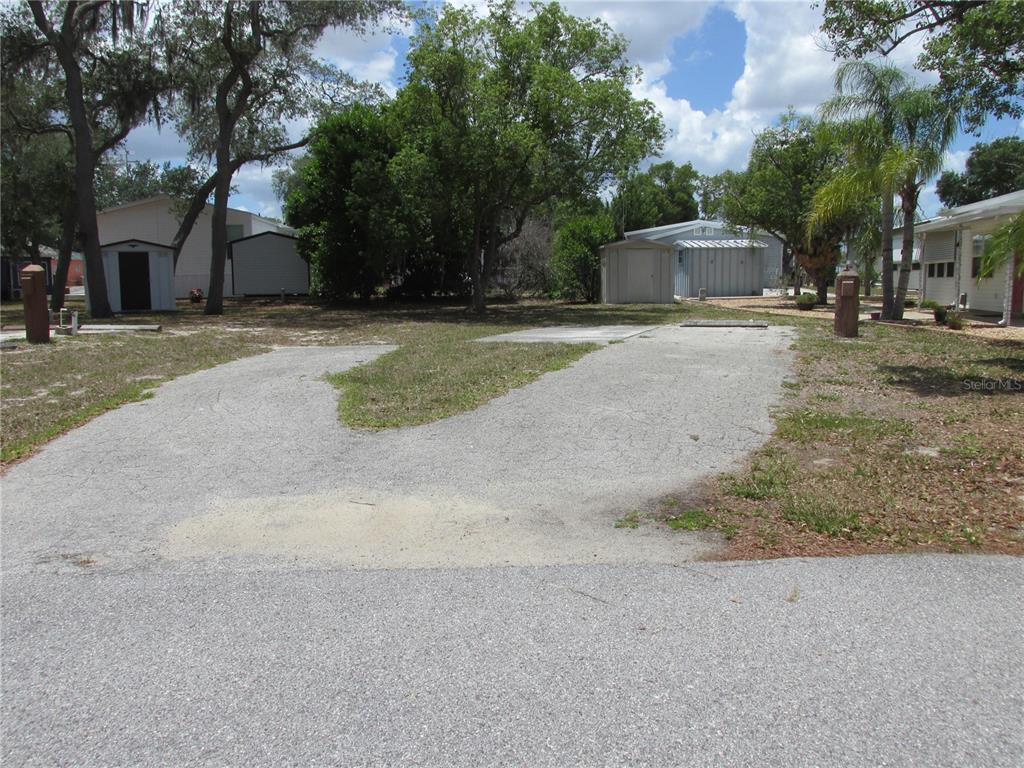 A gravel driveway leads to a vacant lot with a small shed and mature trees — 20 SILVER DOCTOR LANE, LAKE WALES, FL
