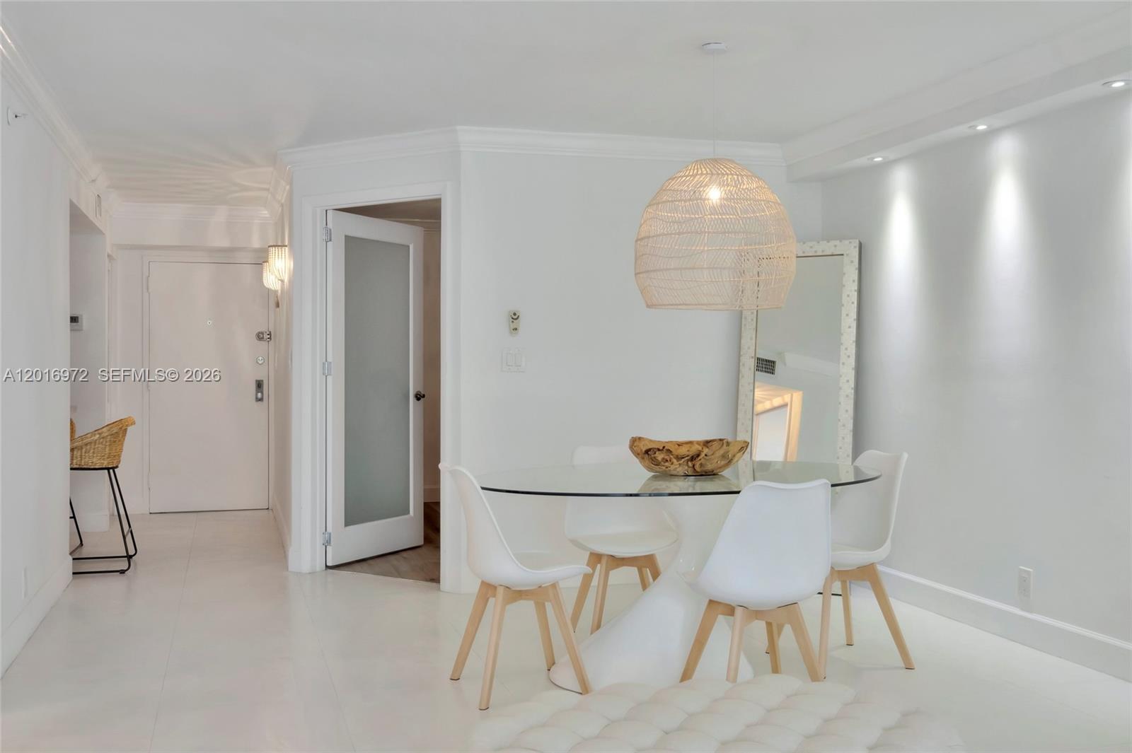 A dining area features a glass-topped table, four white chairs, and a woven pendant light — 2401 Collins Ave # 1805, Miami Beach FL 33140, MIAMI BEACH, FL