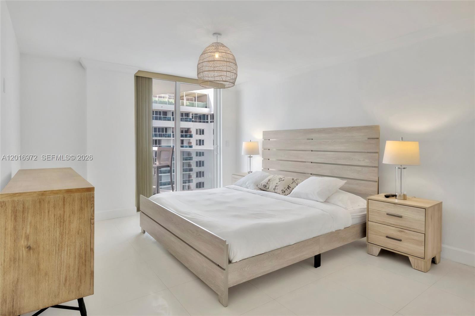 A bedroom features a light wood bed frame, matching nightstands, and a balcony with city views — 2401 Collins Ave # 1805, Miami Beach FL 33140, MIAMI BEACH, FL