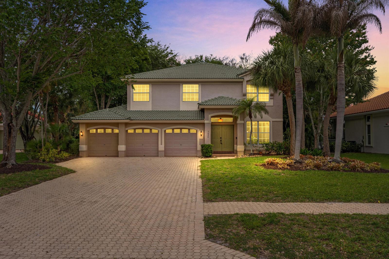 A two-story house with a three-car garage, green tile roof, and a paved driveway — 5020 SW Elk River Court, Palm City FL 34990, PALM CITY, FL