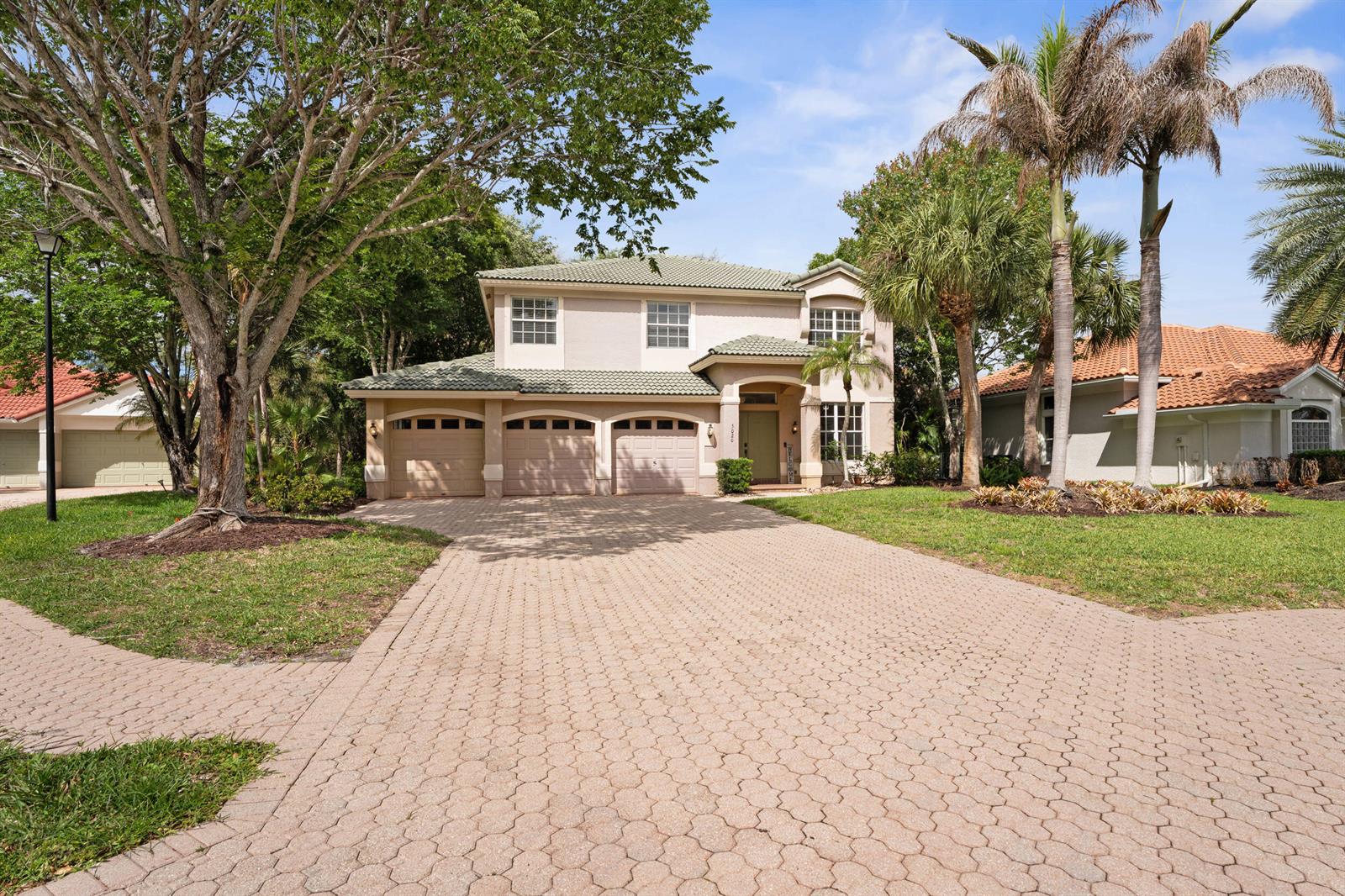 A two-story house with a three-car garage and a paved driveway sits on a lawn — 5020 SW Elk River Court, Palm City FL 34990, PALM CITY, FL