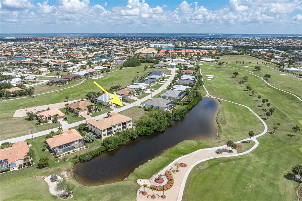 An aerial view shows a multi-story residential building and houses situated along a golf course — 2053 PADRE ISLAND DRIVE, PUNTA GORDA, FL