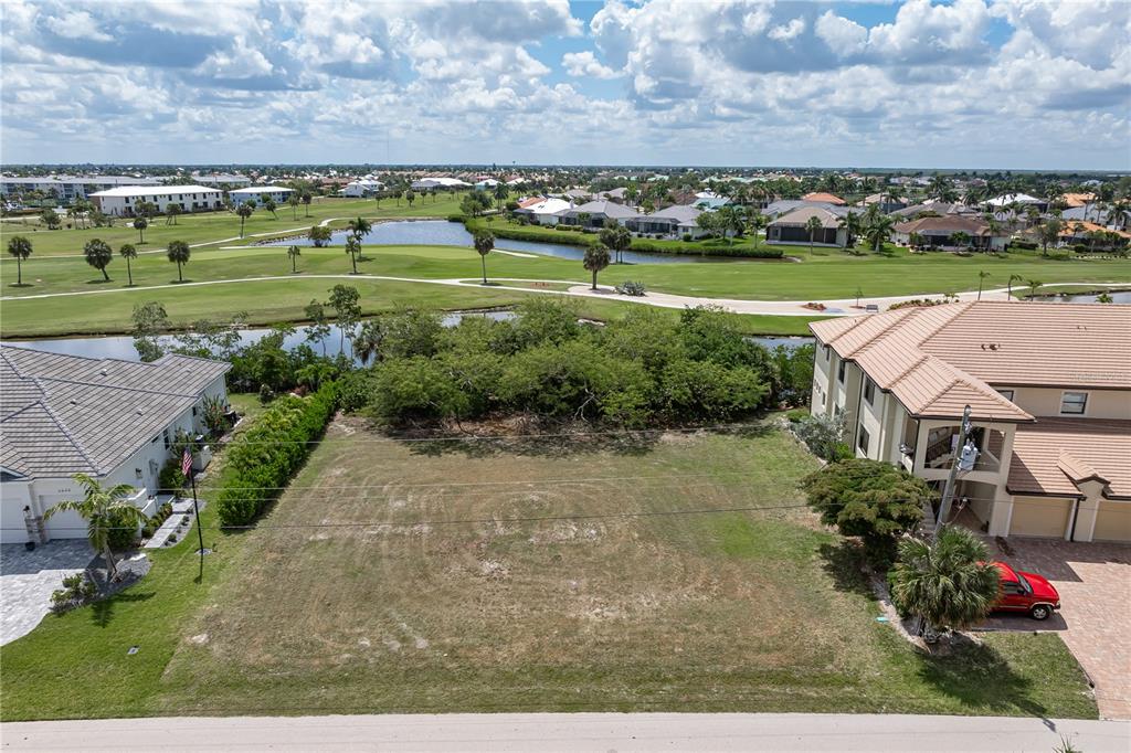 An aerial view shows a vacant residential lot situated between two houses near a golf course — 2053 PADRE ISLAND DRIVE, PUNTA GORDA, FL