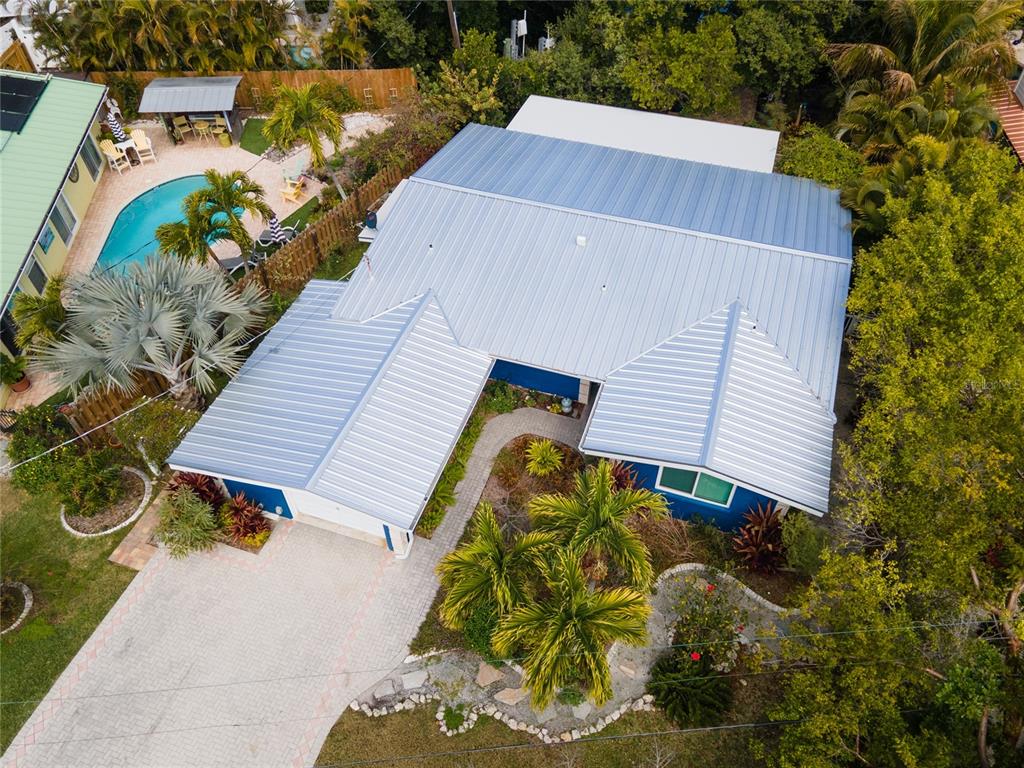 An aerial view shows a blue house with a metal roof, driveway, and swimming pool — 504 58TH STREET, HOLMES BEACH, FL