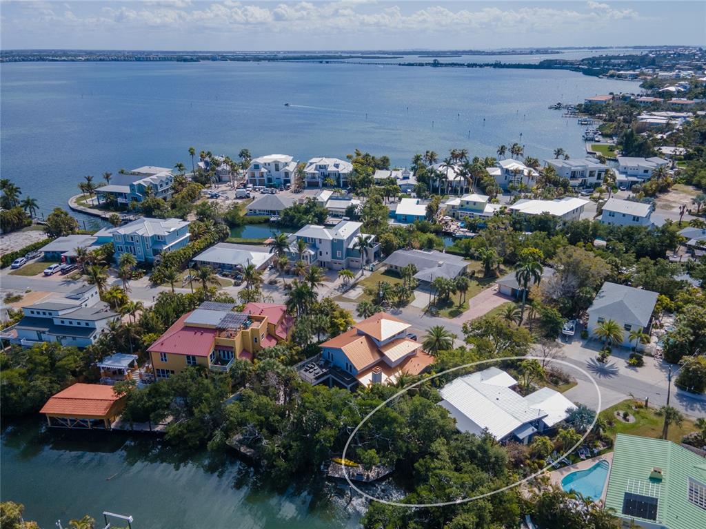 An aerial view shows a waterfront house with a white roof surrounded by lush trees — 504 58TH STREET, HOLMES BEACH, FL