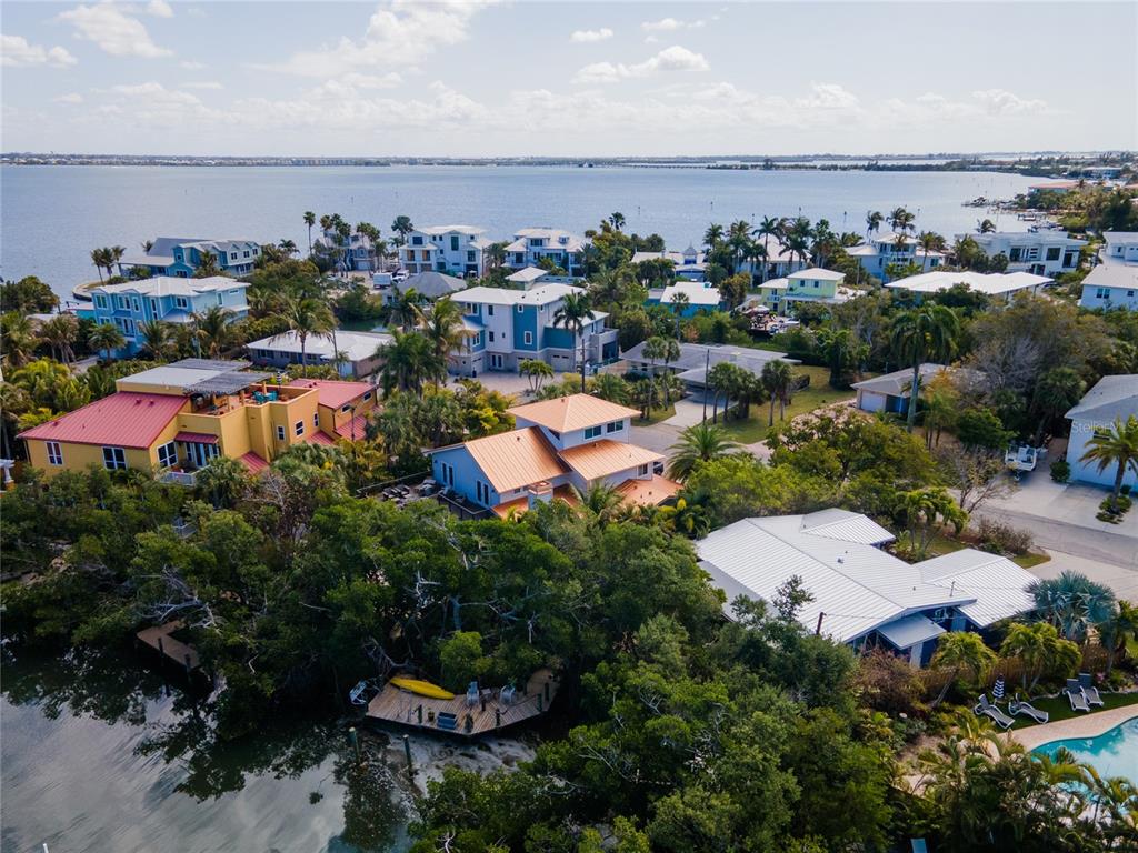 An aerial view shows several waterfront houses surrounded by lush trees near a large bay — 504 58TH STREET, HOLMES BEACH, FL
