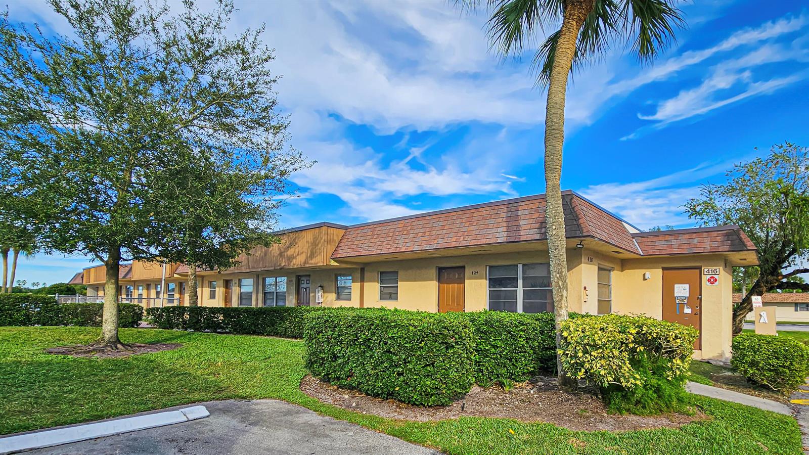 A single-story commercial building with a brown shingled roof, tan stucco walls, and landscaping — 416 Lakeside Drive # 129, Margate FL 33063, MARGATE, FL