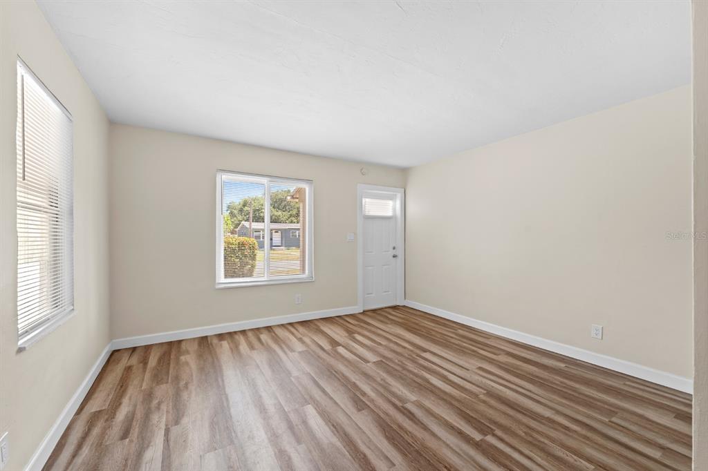 An empty room features light-colored walls, wood-look flooring, two windows, and a white door — 4654 13TH AVENUE S, ST PETERSBURG, FL