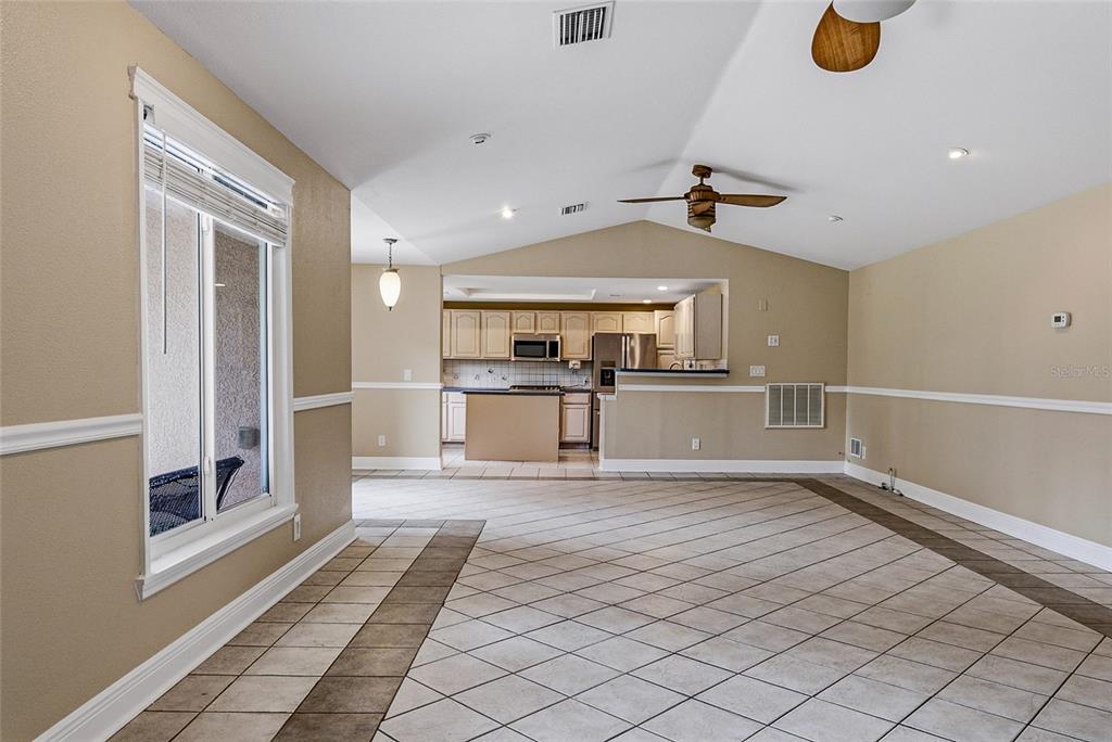 A spacious living area with tile flooring leads to an open kitchen with light cabinetry — 8205 WESTRIDGE DRIVE, TAMPA, FL