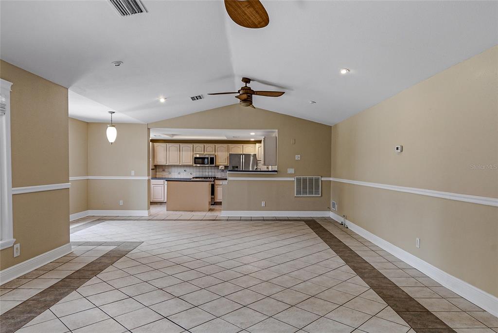 A spacious room with vaulted ceilings, tile flooring, and an open view into the kitchen — 8205 WESTRIDGE DRIVE, TAMPA, FL