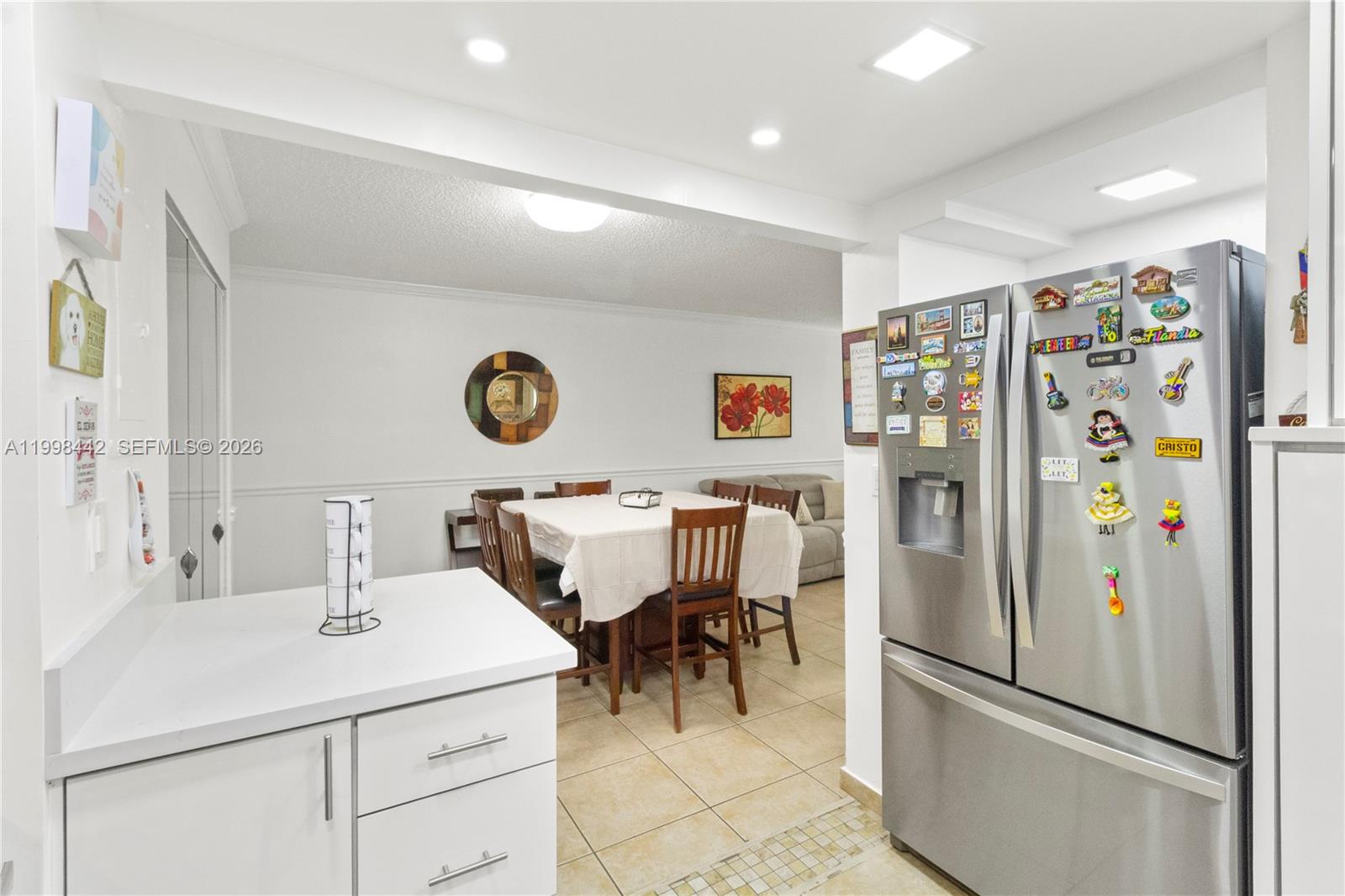 A kitchen with white cabinets and a stainless steel refrigerator opens to a dining area — 840 NW 87th Ave # 405, Miami FL 33172, MIAMI, FL