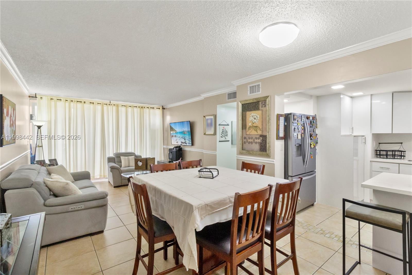 A dining area with a square table sits adjacent to a living room and kitchen — 840 NW 87th Ave # 405, Miami FL 33172, MIAMI, FL