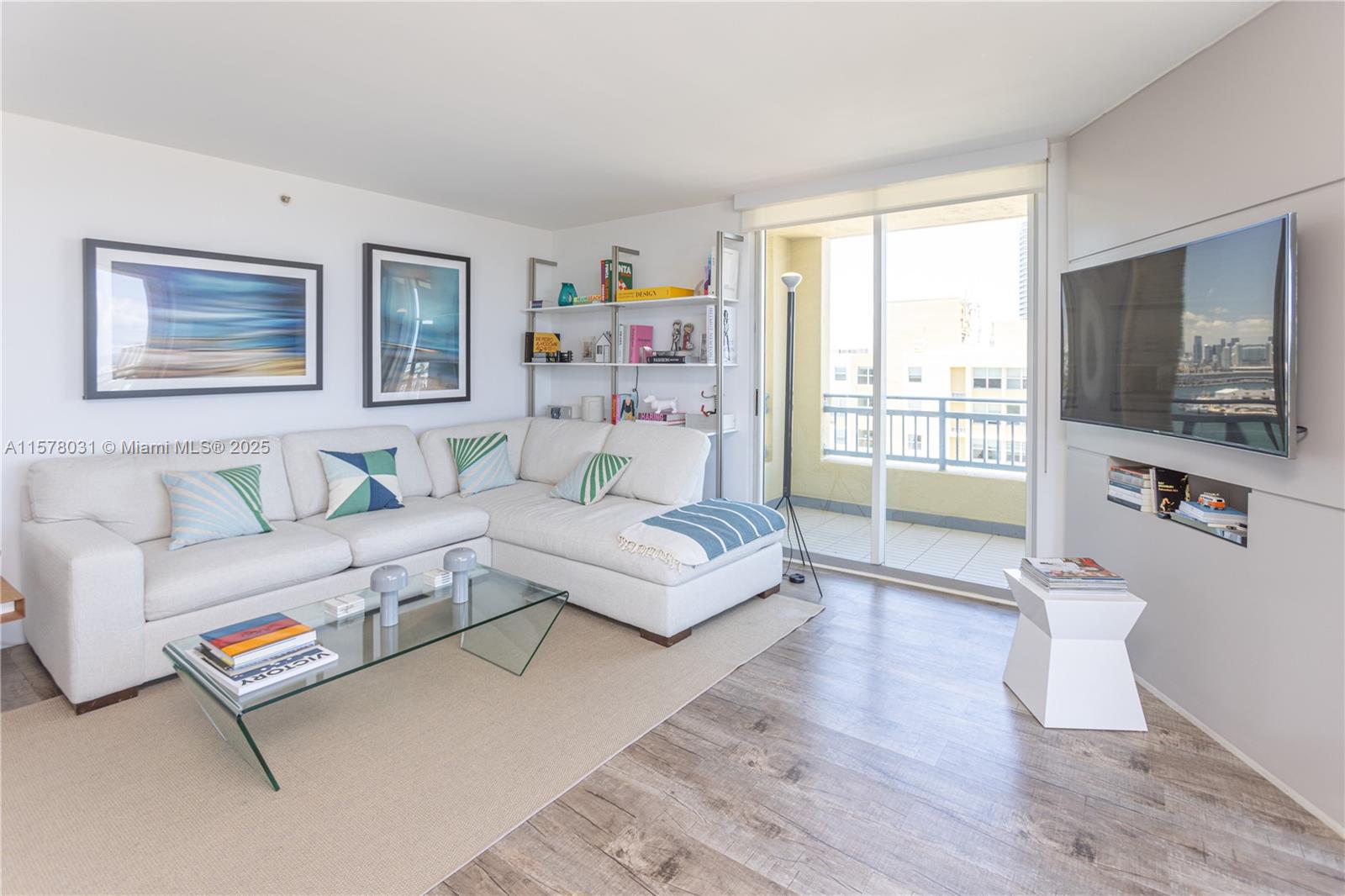 A living room features a white sectional sofa, glass coffee table, and a wall-mounted television — 90 Alton Rd # 1411, Miami Beach FL 33139, MIAMI BEACH, FL