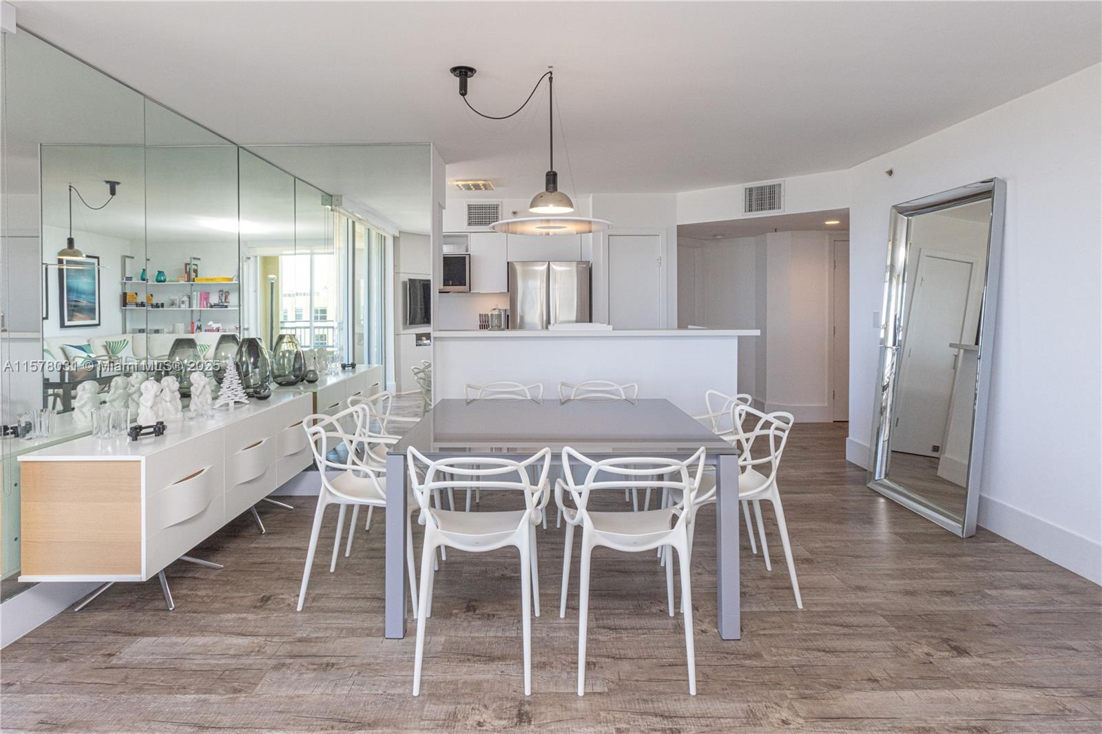 A dining area features a gray table with white chairs and a large wall mirror — 90 Alton Rd # 1411, Miami Beach FL 33139, MIAMI BEACH, FL