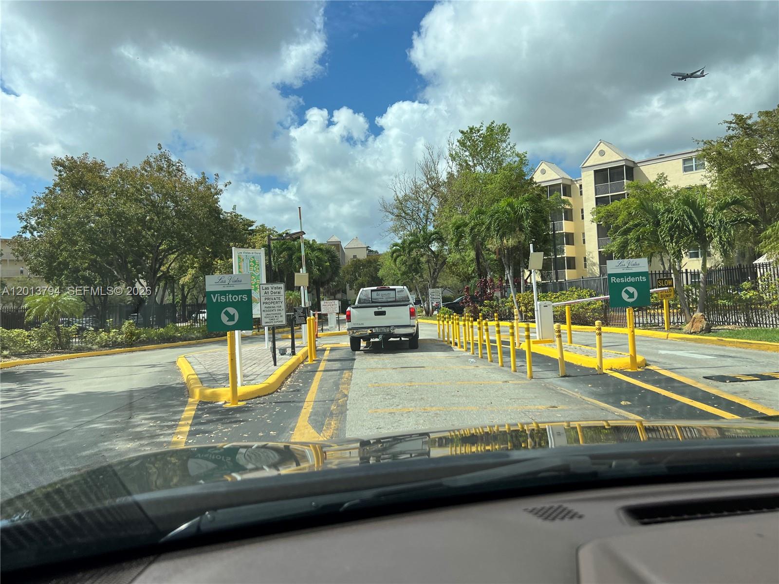 A white pickup truck approaches the gated entrance of a residential community with signage — 8373 Lake Dr # 202, Doral FL 33166, DORAL, FL