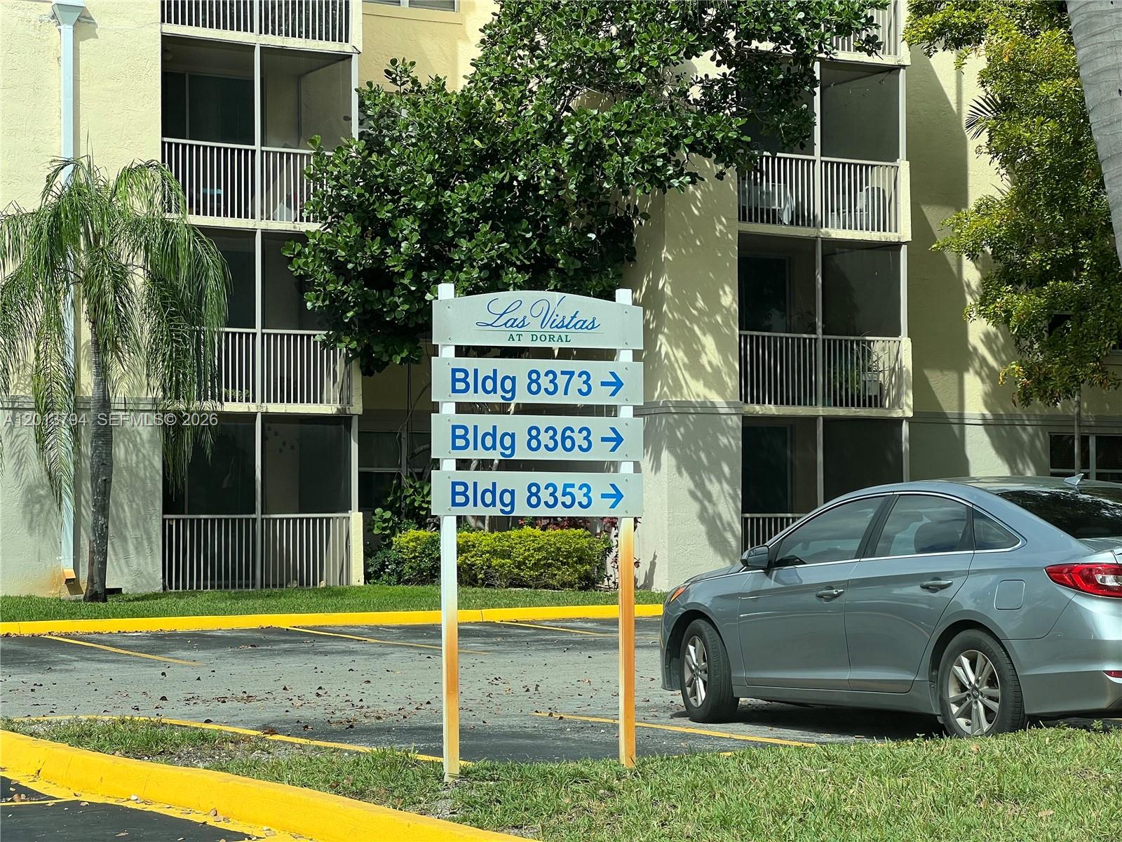 A sign for Las Vistas at Doral stands in a parking lot before an apartment building — 8373 Lake Dr # 202, Doral FL 33166, DORAL, FL